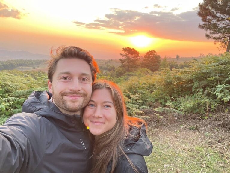 Een selfie van een lachende Niels en ik. Achter ons zie je de zonsondergang in de bergen