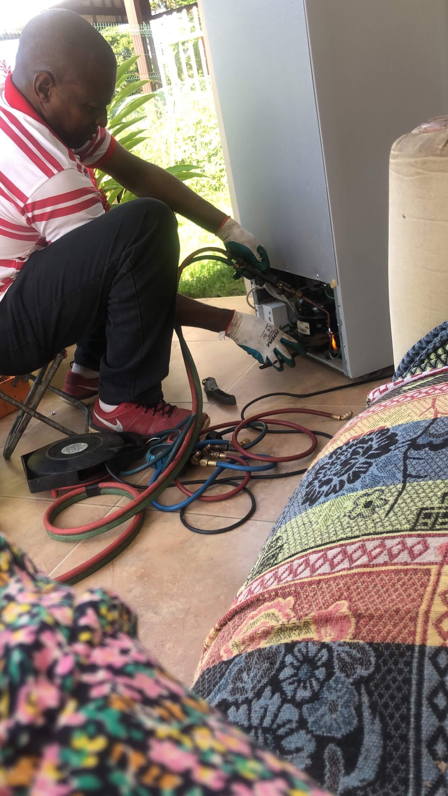 De koelkast wordt gemaakt. De koelkast is aan de onderkant van de achterkant open gemaakt en een technician is met allemaal draden bezig om de koelkast te maken