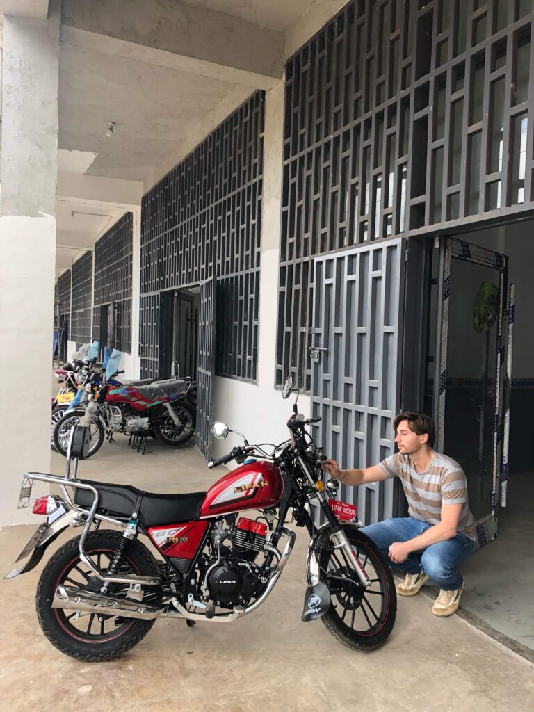 Ons Liefje! De motor is rood met zwart. Niels zit er gehurkt naast.