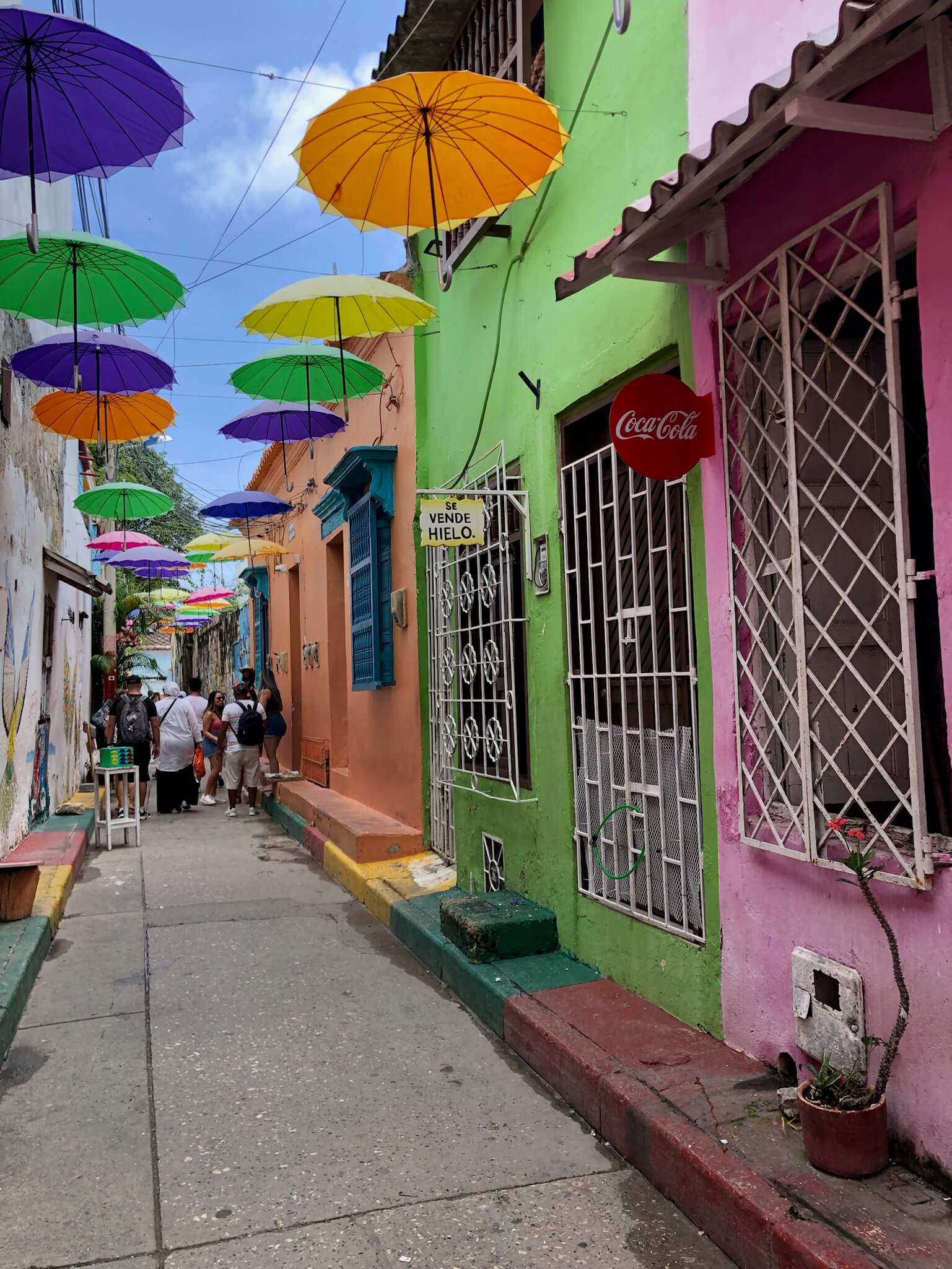 Een schattig kleurrijk straatje in Getsemaní met gekleurde huisjes en gekleurde paraplu's die in de lucht hangen