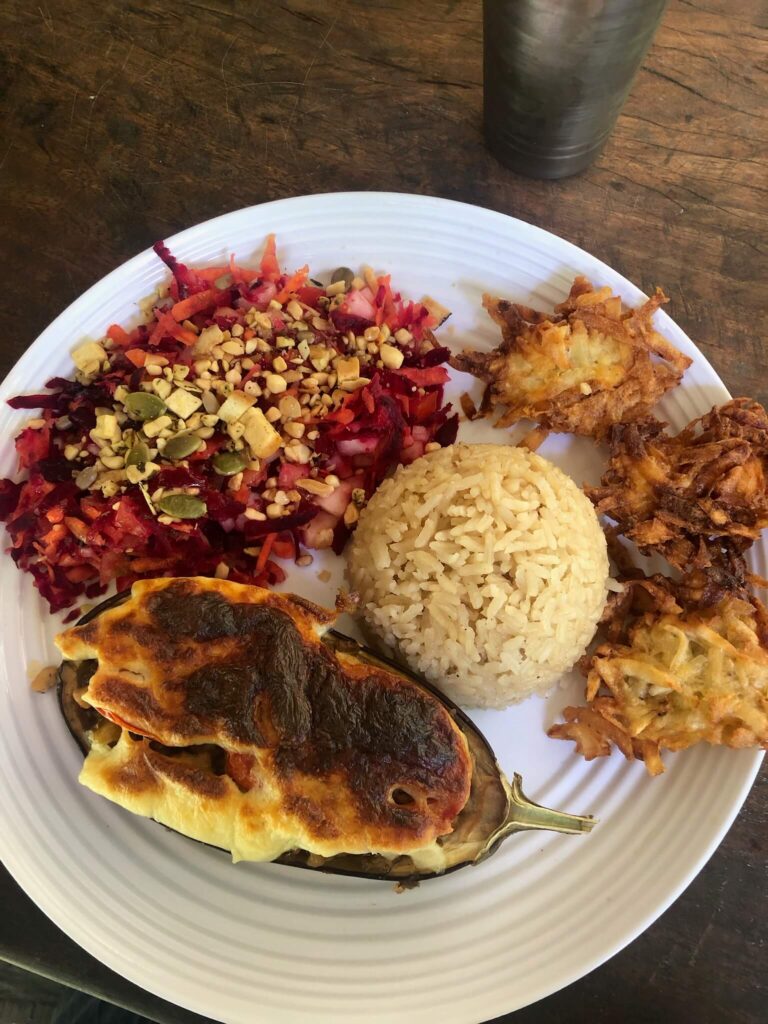 Bord met eten: er ligt rijst, een halve courgette met gesmolten kaas, een salade en wat kleine deegbolletjes