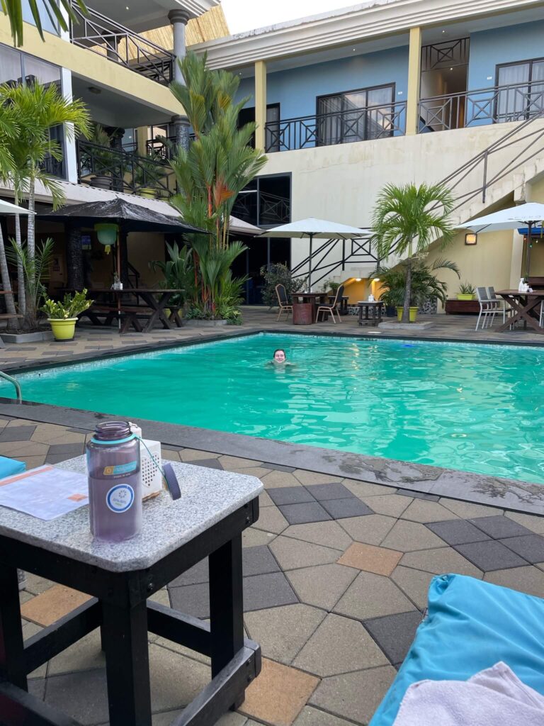 Een foto van het zwembad waar ik in de verte aan het zwemmen ben en omhoog kijk in de camera.