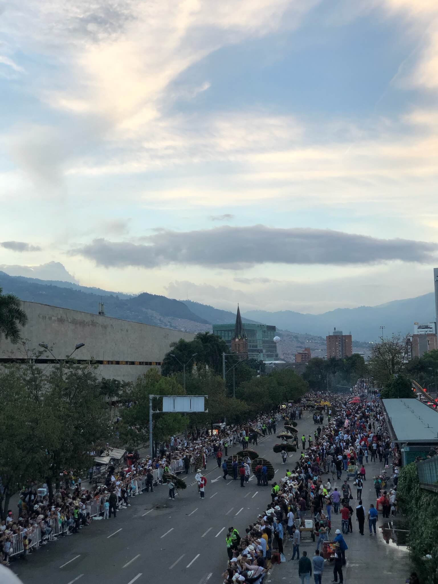 Een straat in Colombia is afgezet. Er loopt een bloemenparade overheen met prachtige grote bloemstukken