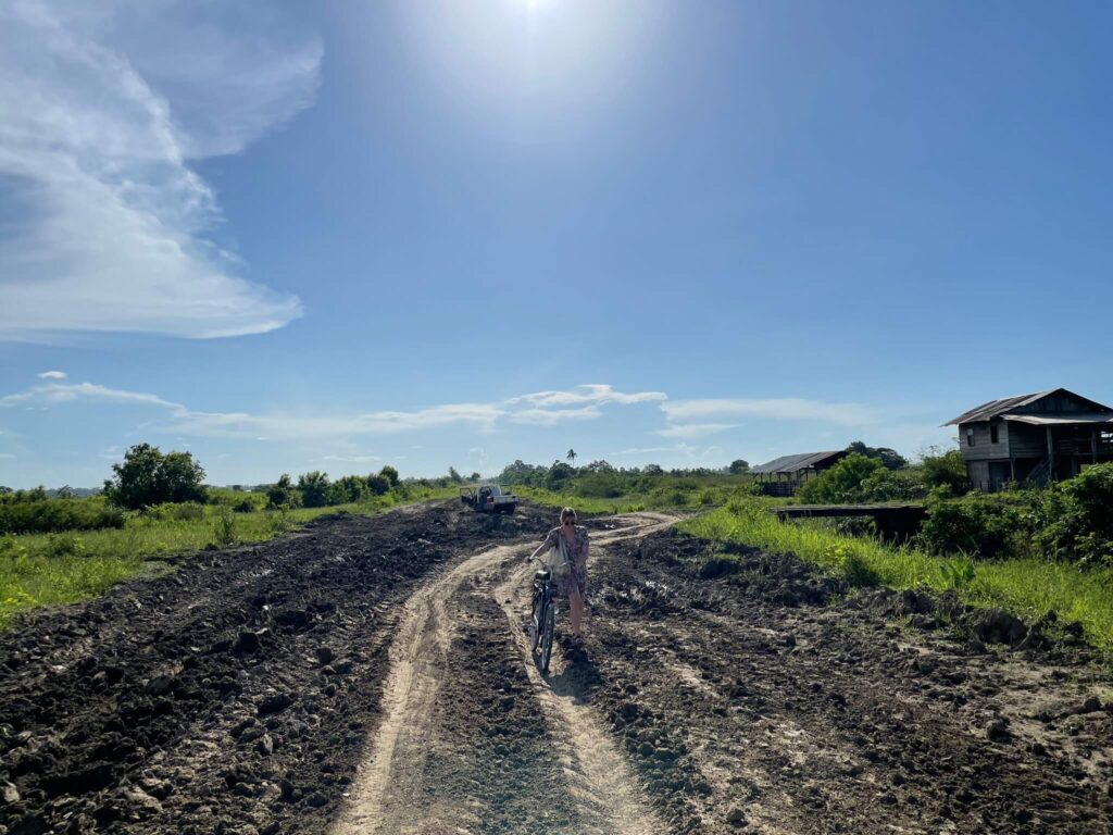 Ik loop met de fiets aan m'n hand door de modder te ploeteren. De lucht is blauw