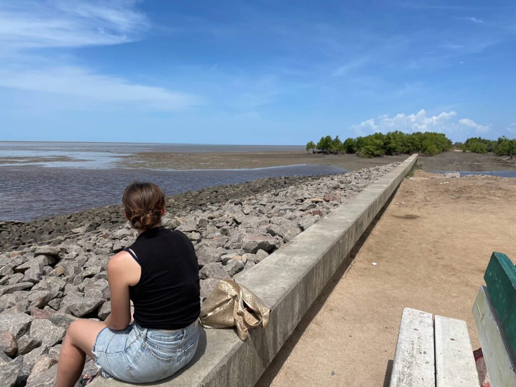De zeedijk! Ik zit op een stenen muurtje met voor mij allemaal stenen. Na de stenen ligt de rivier