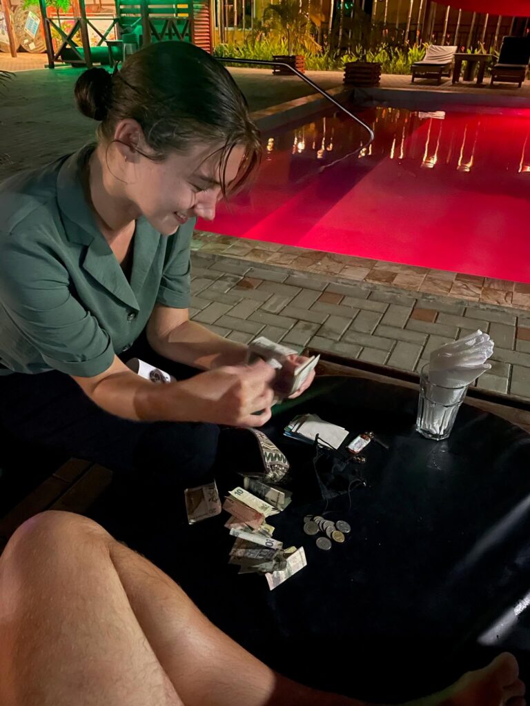 Ik zit voorovergebogen aan een salontafel en zit lachend alle geldbiljetten te tellen die op tafel liggen