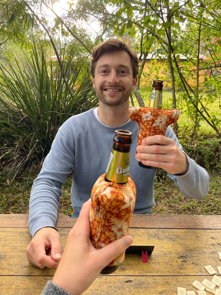 Ik steek m'n biertje naar Niels uit om te cheersen. Hij lacht in de camera en houdt z'n biertje omhoog. Om de biertjes zitten leuke warmhouddingetjes