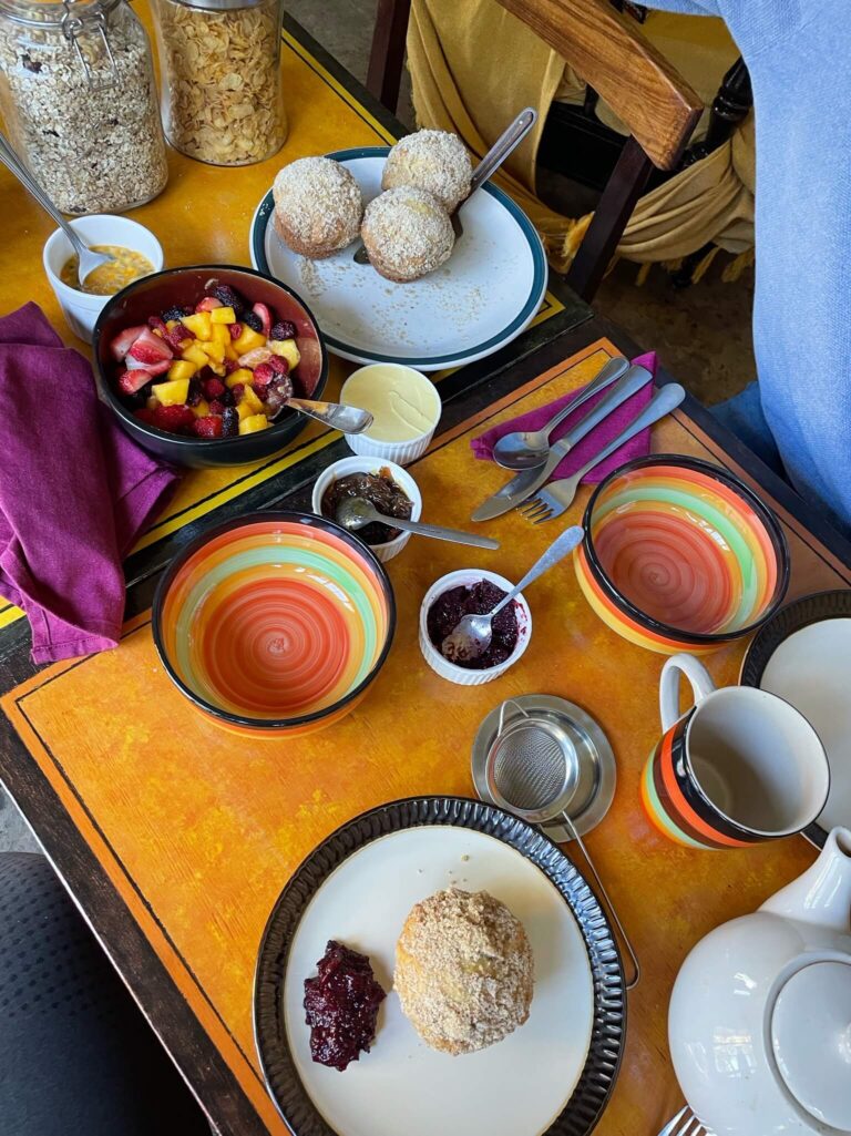 Een gedekte tafel met 2 borden, papaya muffins en een bak fruit