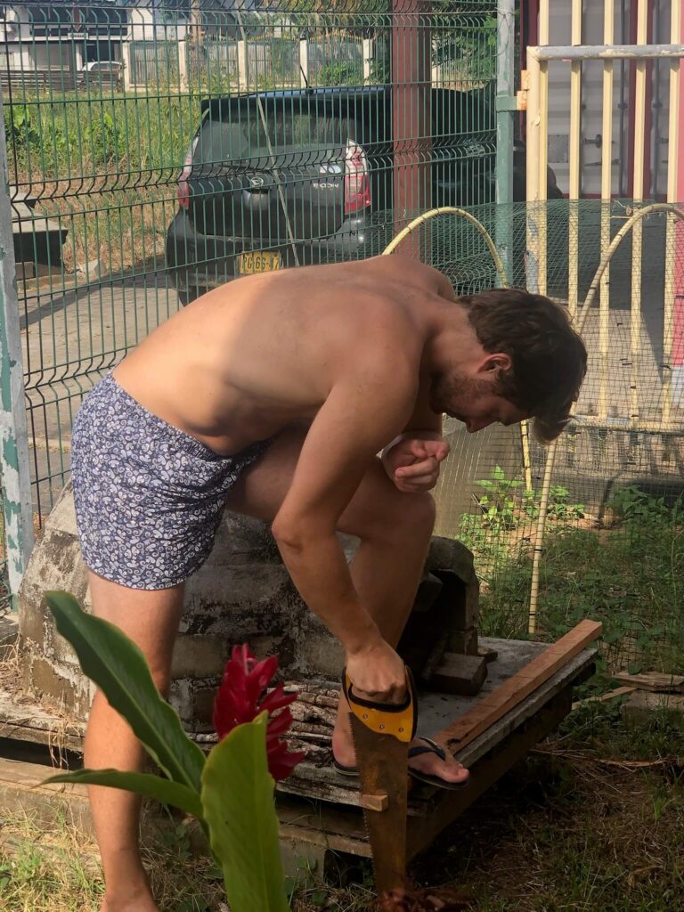 Niels is de muziekstandaard aan het maken: hij staat voorovergebogen en is met een zaag in hout aan het snijden