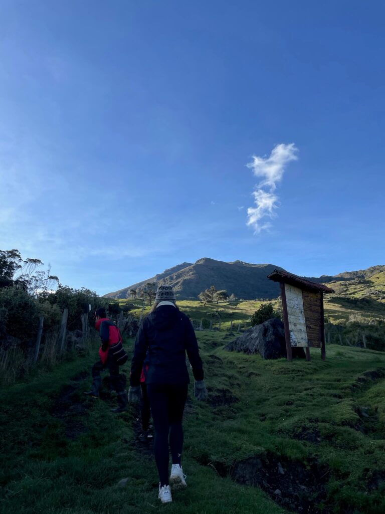 3 mensen achter elkaar lopend door de bergen met daarboven een strakblauwe lucht