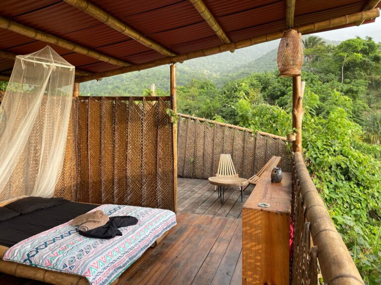 Open kamer met een groot bed middenin de groene heuvelachtige omgeving