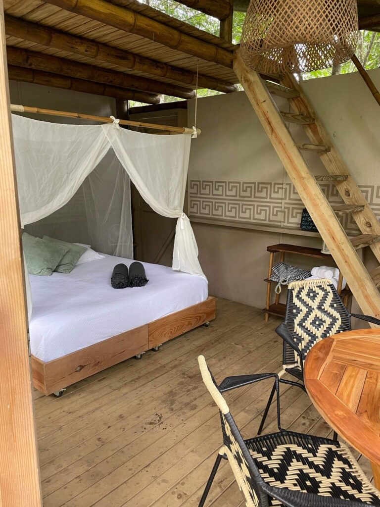 Je ziet hier onze houten kamer met een groot bed met klamboe en twee stoeltjes ervoor