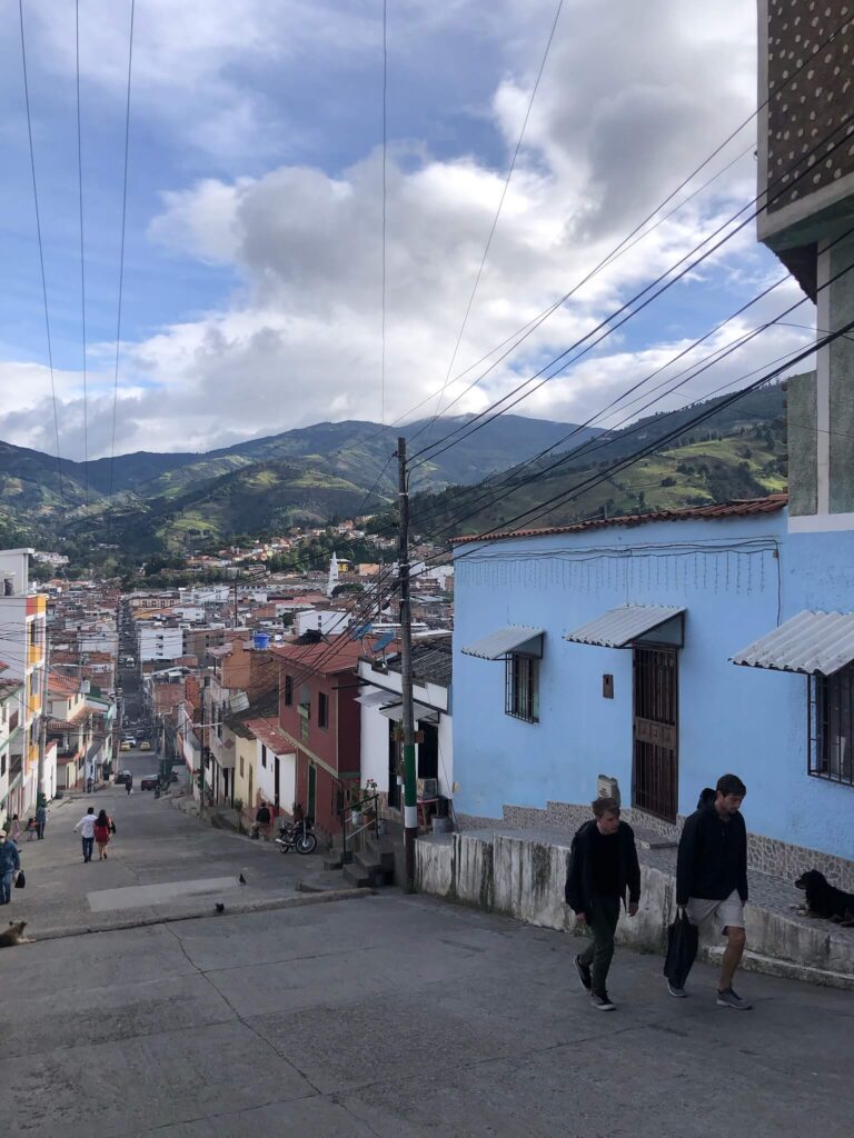 Een straatje in Pamplona die wat omhoog loopt. De foto is genomen vanaf de bovenkant van het straatje en kijkt dus naar beneden naar gezellige gekleurde huisjes en bergen in de verte