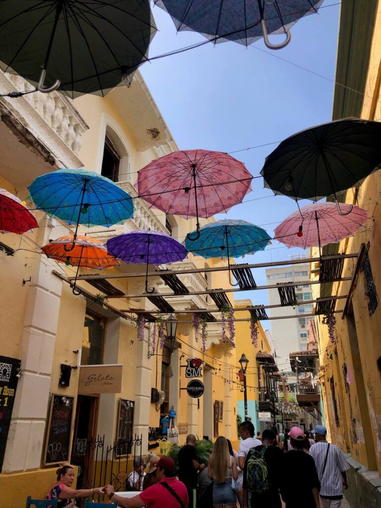 Een smal wandelstraatje in Santa Marta met gekleurde paraplu's die tussen de huizen in de lucht hangen als een soort slinger