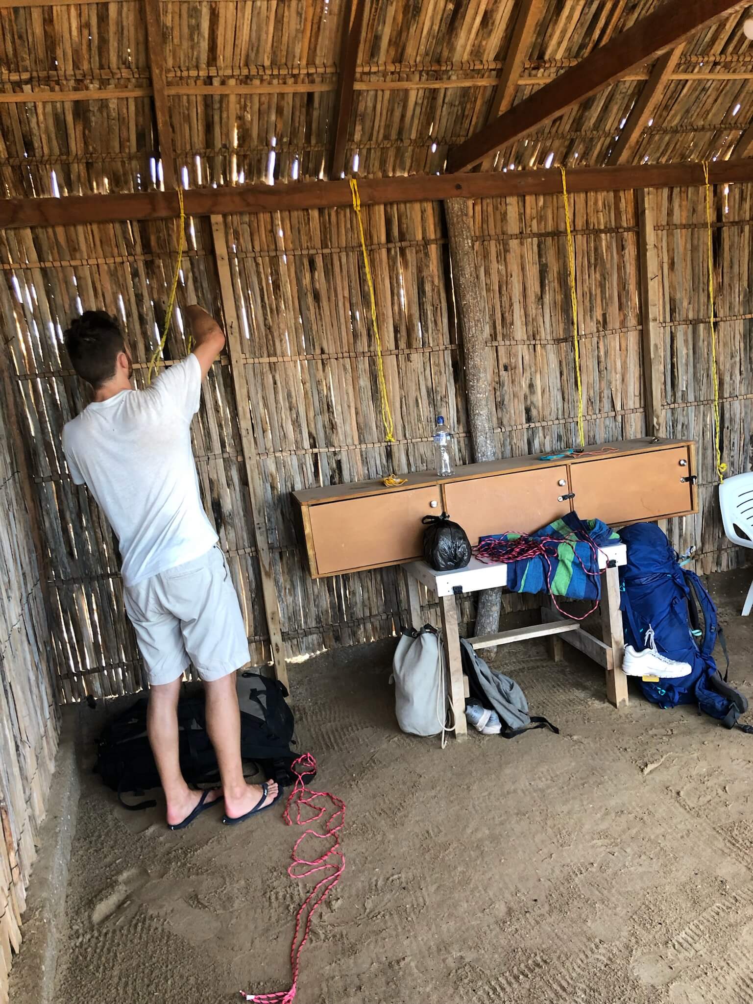 Niels hangt 2 klamboes op in een rieten hutje