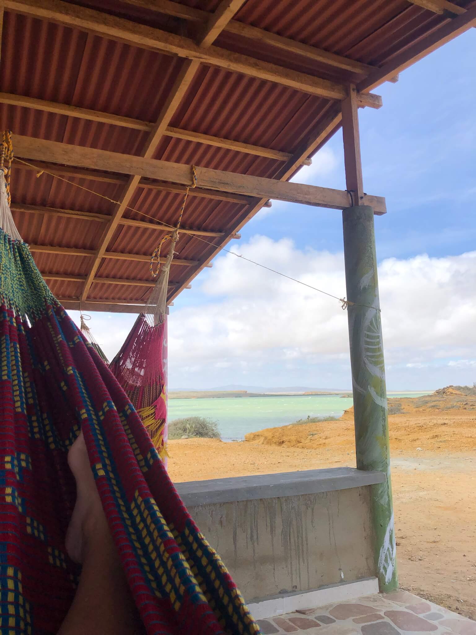 Je ziet hier 2 hangmatten hangen met uitzicht op het strand en de zee