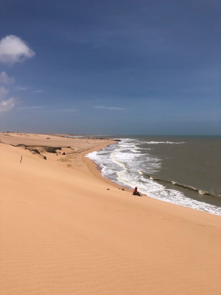 Je ziet hier een heel wit strand met daarnaast de zee waarvan de golven op het strand neerkloppen