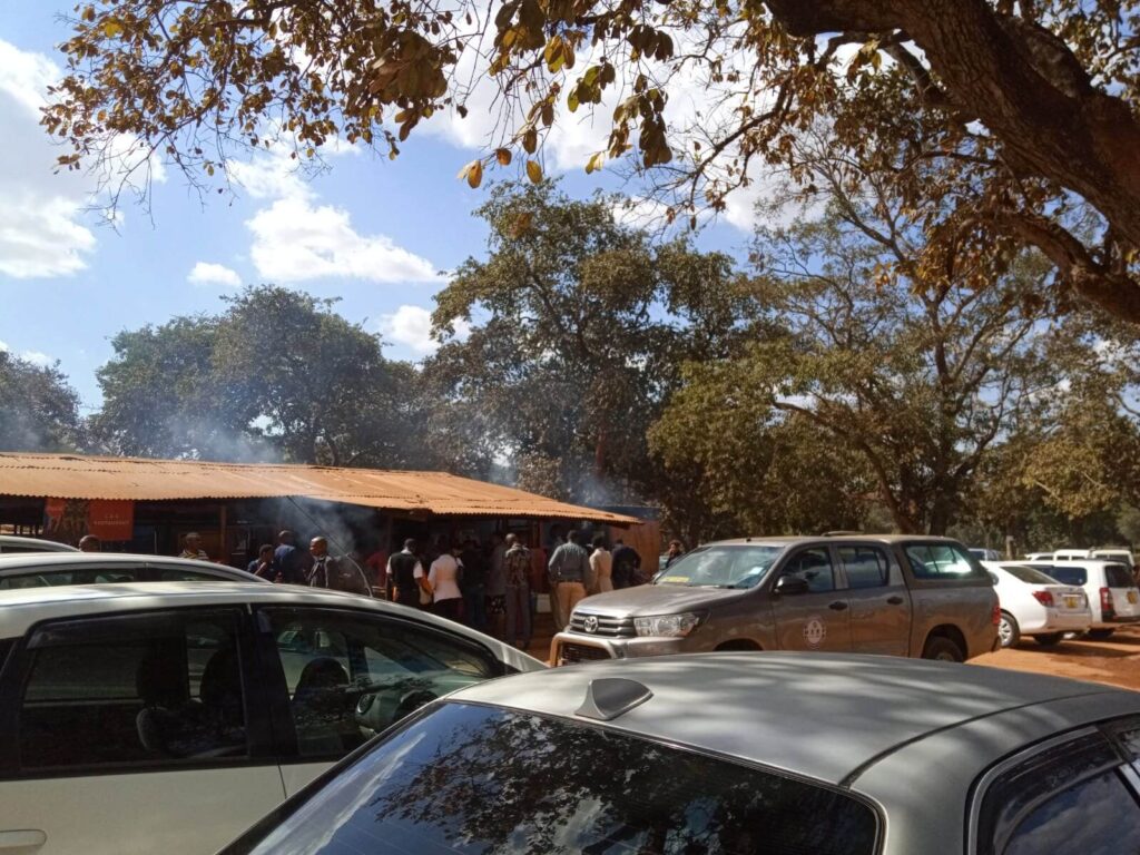 Je ziet hier meerdere auto's achter elkaar staan met daarachter een tentje waar allemaal mensen lunch aan het bestellen zijn