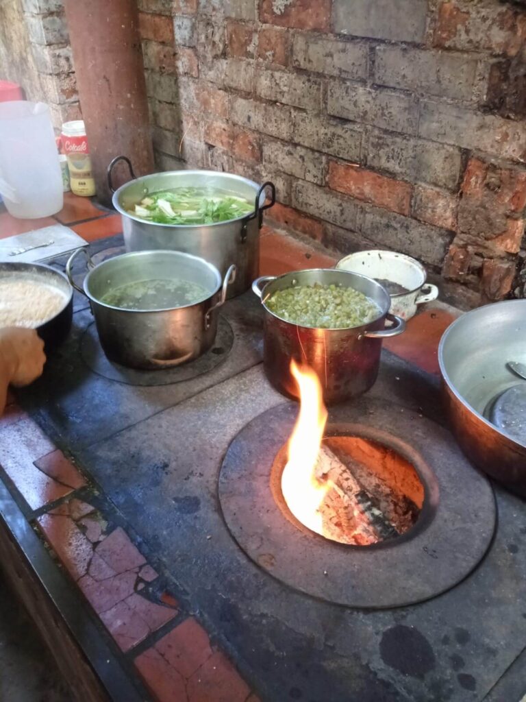 Een foto van een vuurtje met 3 gevulde pannen ernaast