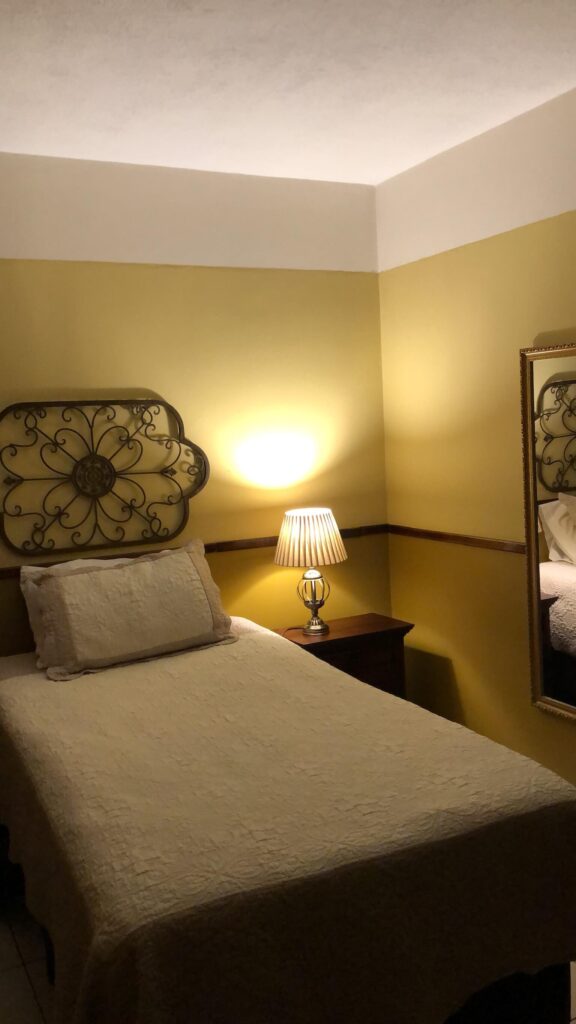 De slaapkamer in Guatemala City. Je ziet hier een 1persoonsbed staan met een bedlampje