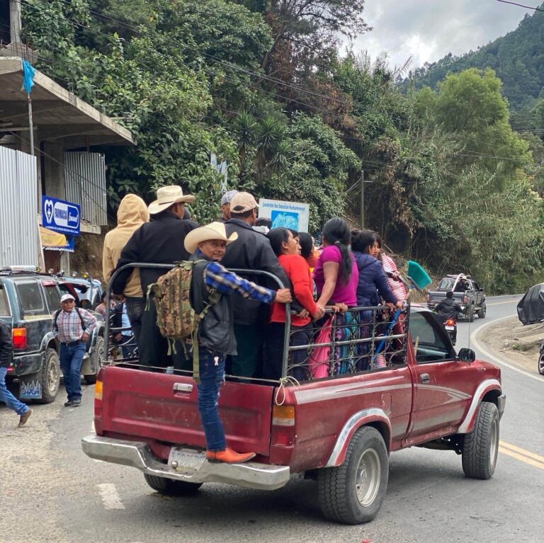 Een jeep met achterin allemaal staande locals.