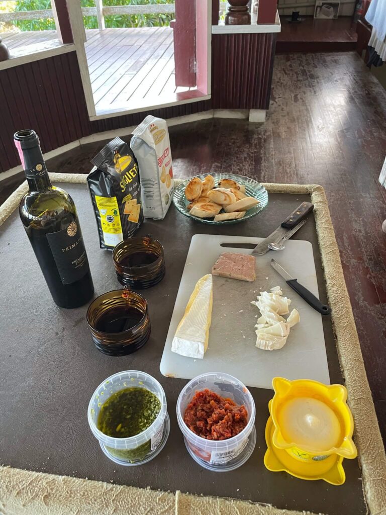 Op de salontafel staat een fles wijn, staat een bakje met toastjes, liggen er 2 kaasjes en paté op een borrelplank en staan daarnaast 3 dipjes