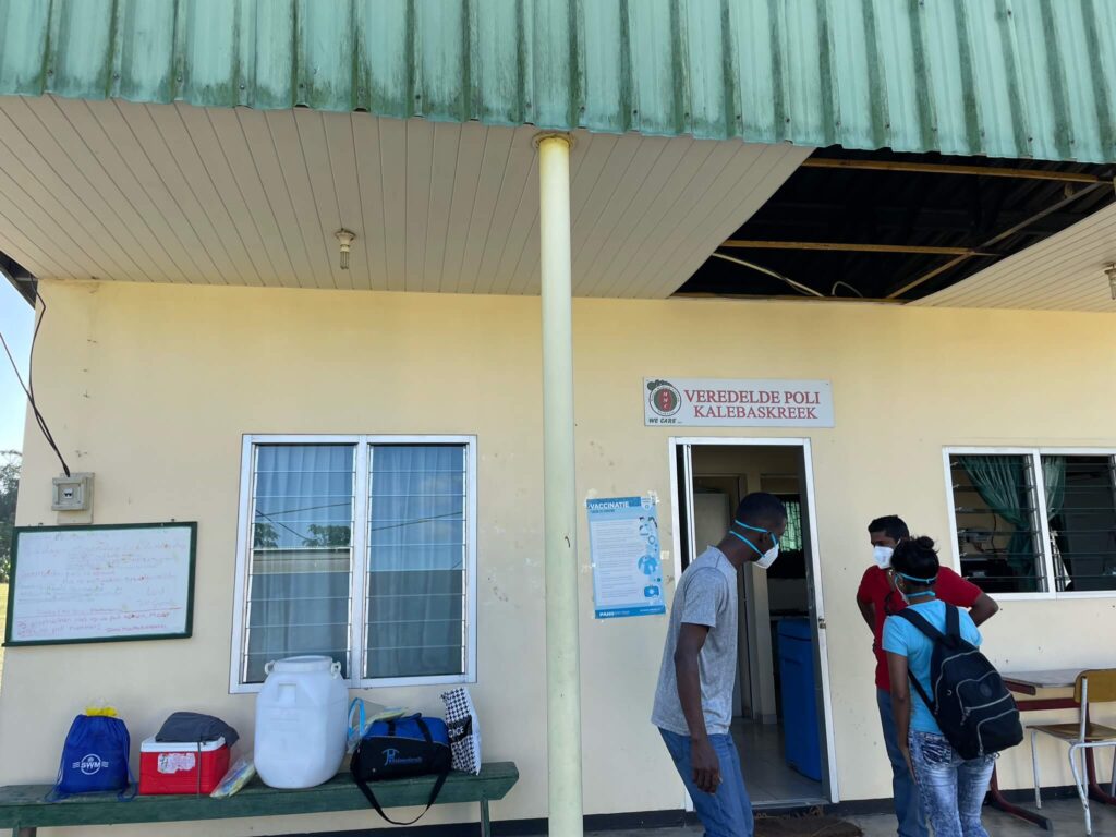 Een foto van de poli in de kalebaskreek. Een beige gestuct huis met daarboven een veranda