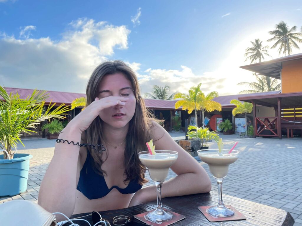 Ik zit aan tafel met m'n hand voor m'n gezicht. Voor me op tafel staan 2 cocktails