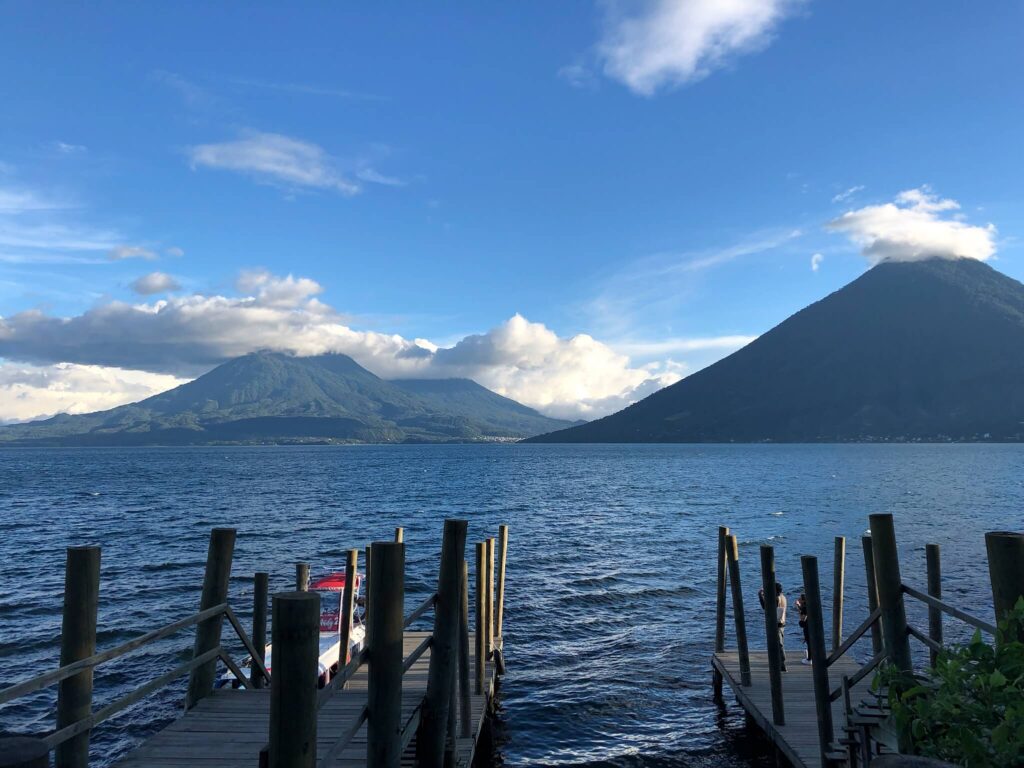 Een foto van het meer met daarachter een berg en vulkaan