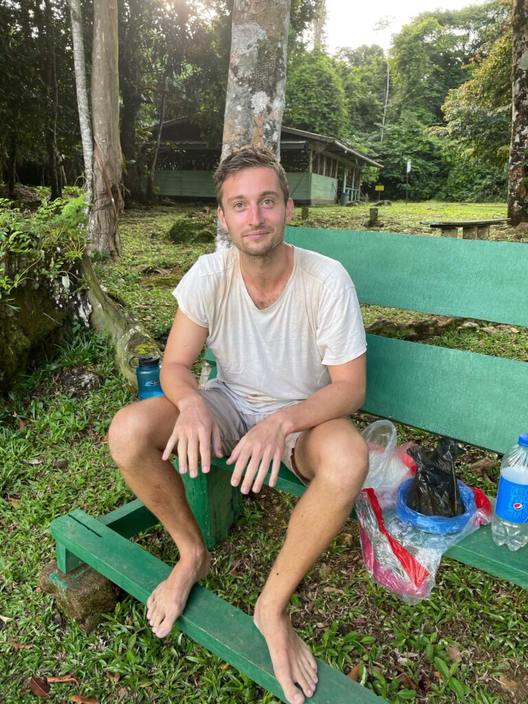 Niels zit volledig verkleumd op een groen houten bankje dat buiten staat. Zijn witte t-shirt is doorweekt van het zweet. Hij steekt z'n handen naar voren die helemaal wit zijn geworden van de kou