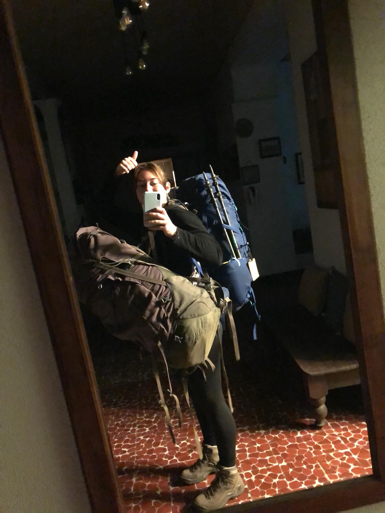 Een foto van mezelf in de spiegel. Ik heb een backpack op m'n rug en een net zo grote backpack op m'n buik