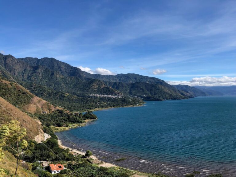 Uitzicht op het meer met aan de linkerkant groene bergen die uitlopen op het meer