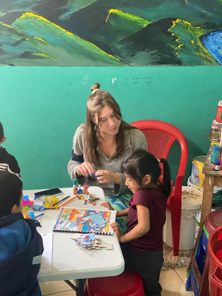 Ik zit aan een tafel met naast mij een lokaal meisje. We zijn aan het kleuren en kleien