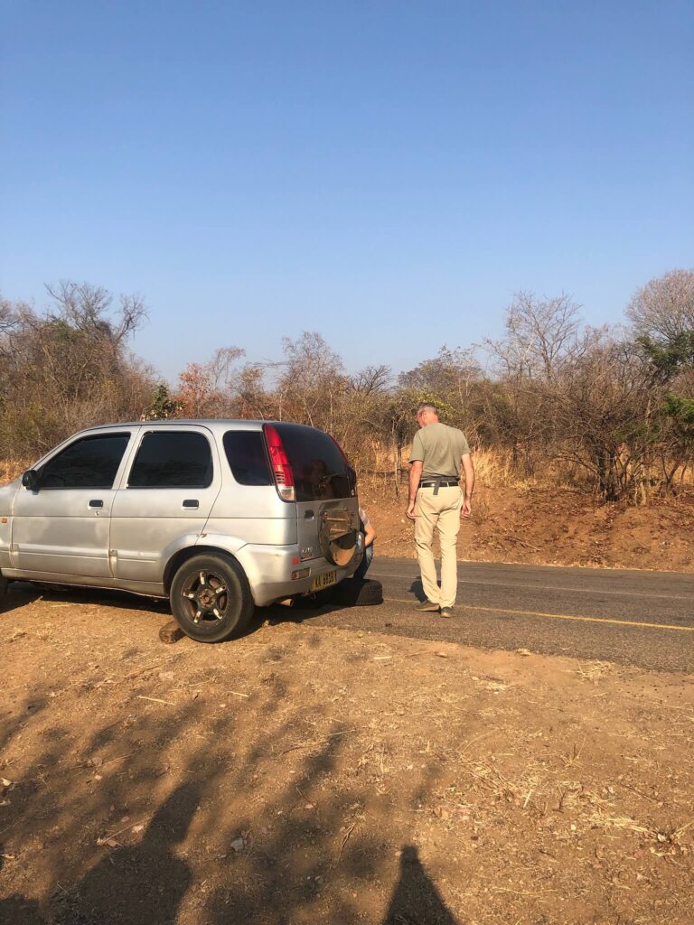 De band van de auto wordt verwisseld. De auto staat langs de kant van de weg