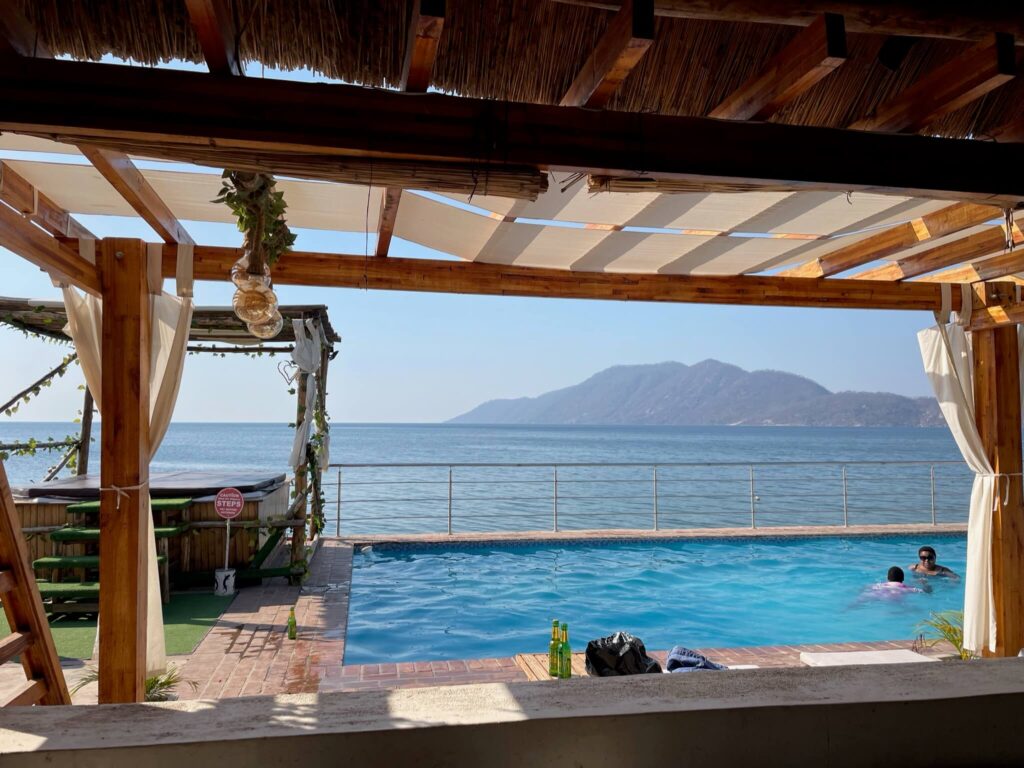 Je ziet hier het buitenzwembad met daarachter het meer en bergen