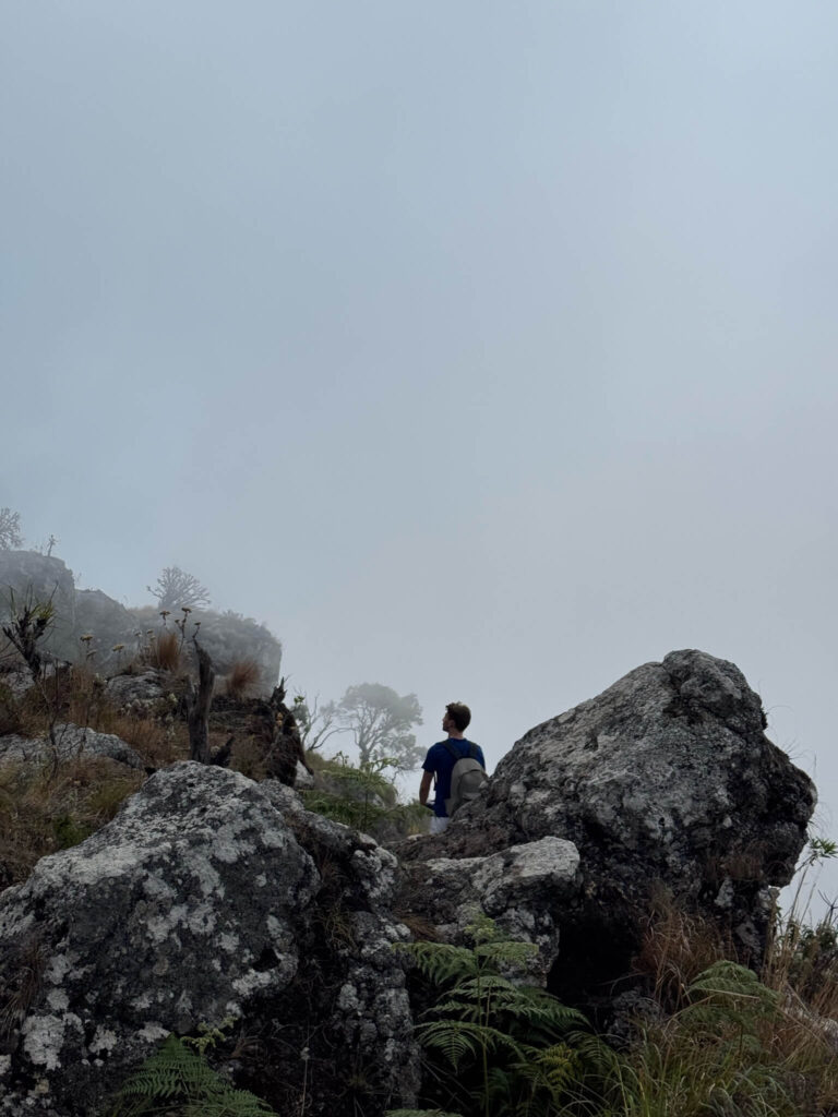 Niels is van de achterkant gefotografeerd tussen een paar stenen in. De lucht is heel mistig dus de foto heeft iets mystieks; je ziet helemaal geen lucht maar slechts een grijze achtergrond