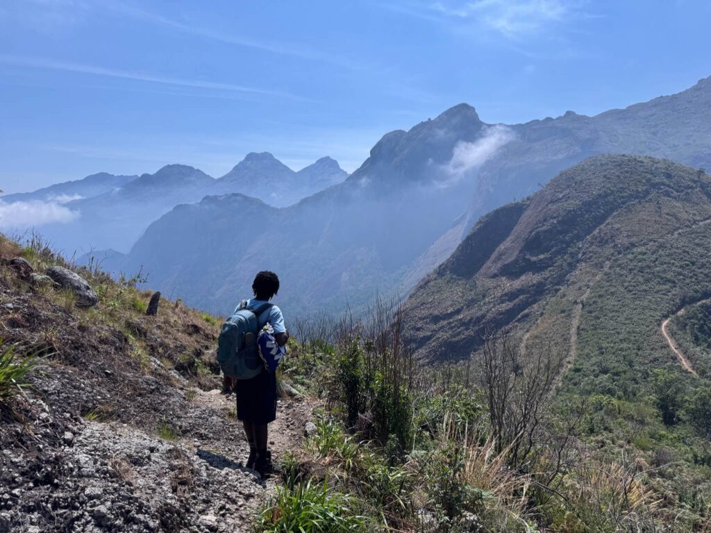 Isaac is van de achterkant gefotografeerd. Voor hem staan meerdere silhouetten van bergen. Prachtig!