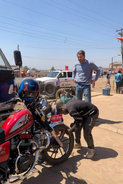 Een lokale man staat voorovergebogen over de band van de motor om de spijker eruit te halen