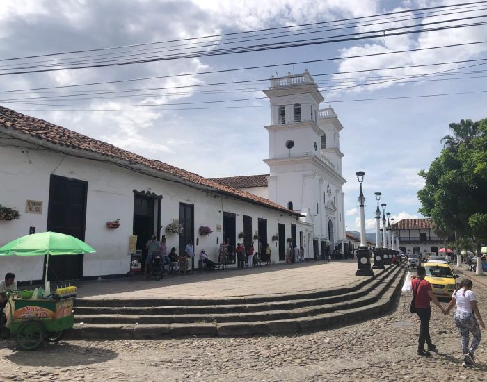Plein in Giron met een witte kerk en mensen die op het plein lopen